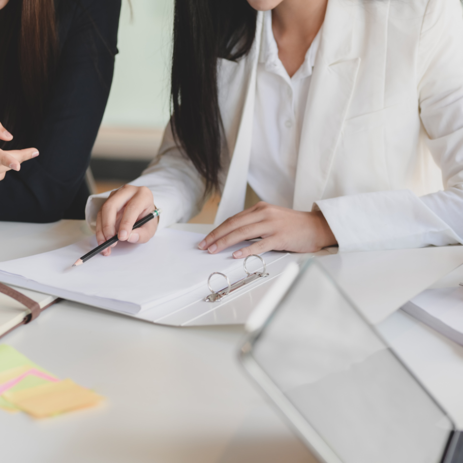 Projektassistenz für kleine- und mittelständige Unternehmen - Nicole Weinert virtuelle Assistentin in Darmstadt Zwei Frauen die vor einem Ordner sitzen und einen Stift in der Handhalten und miteinander sprechen